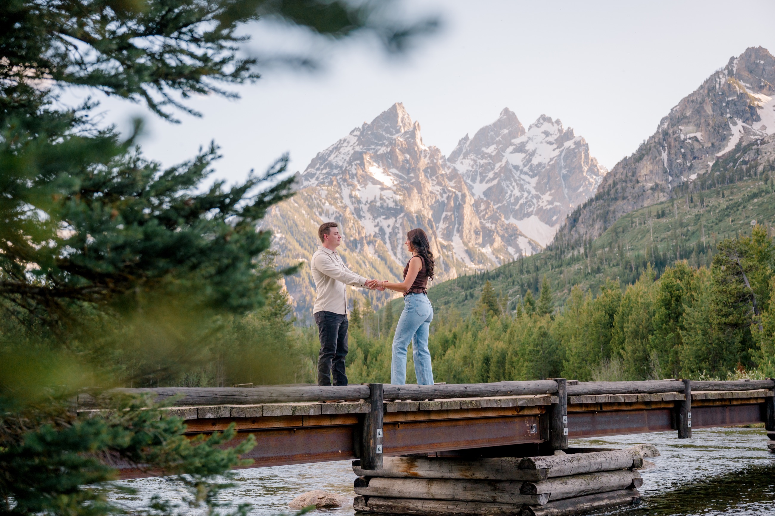Michael and Brooke holding hands on a bridge beneath the mountains
