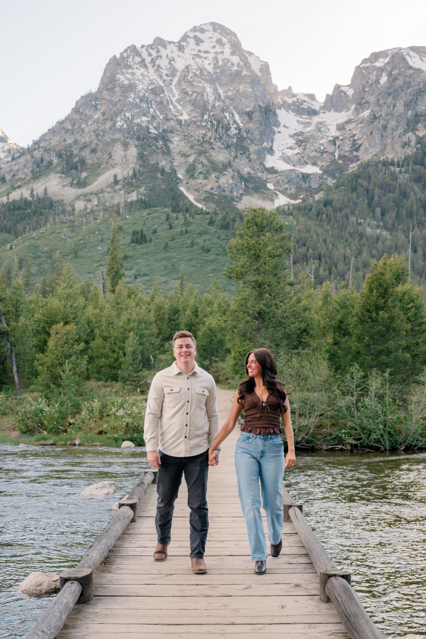 Michael and Brooke walking across a bridge below the mountains