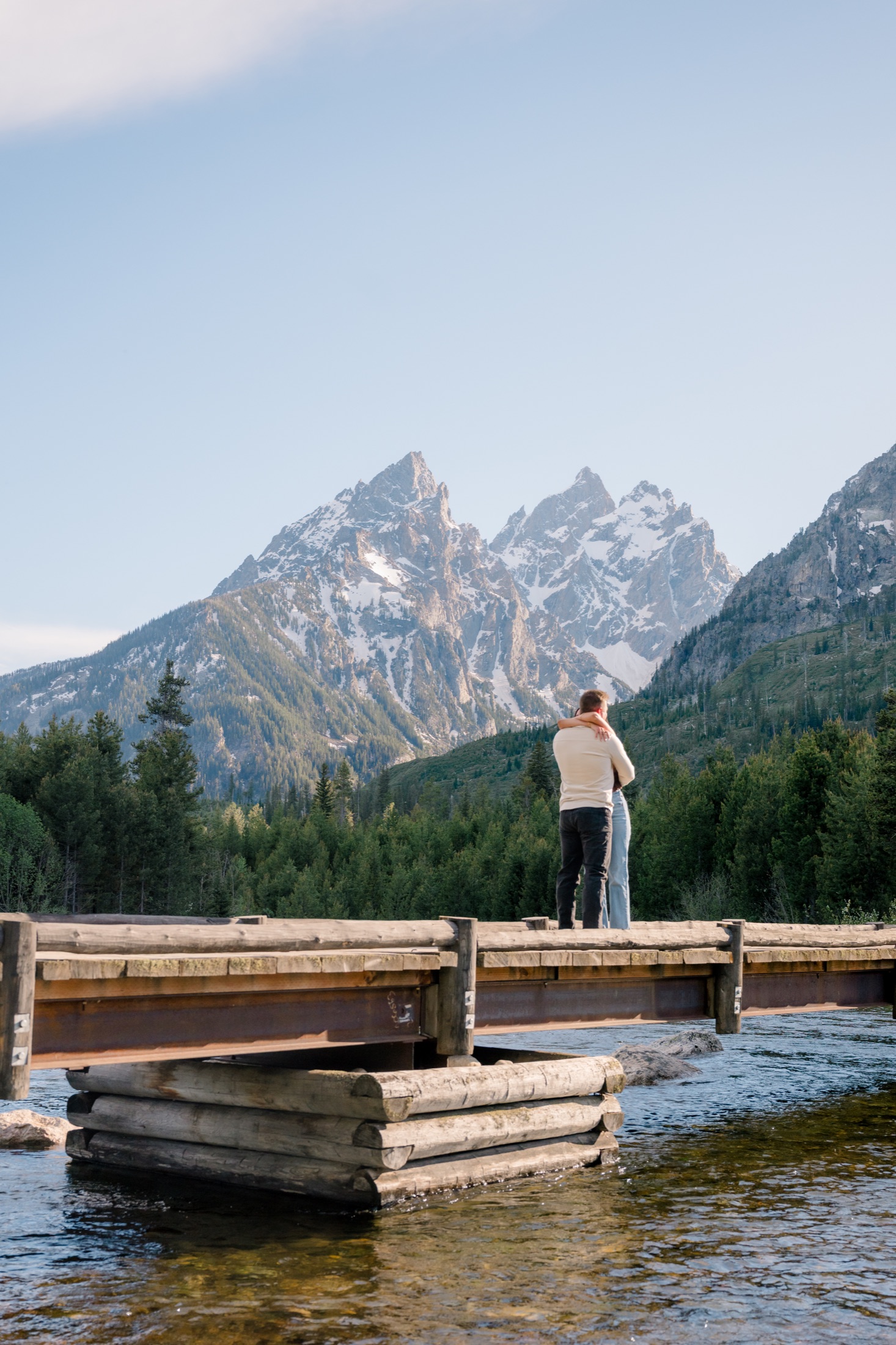 Michael and Brooke embracing on a bridge beneath the Tetons